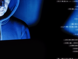 A man in a hoodie in the dim-light symbolizing a hacker breaking into a database
