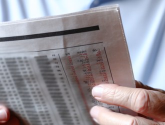 An investor reading a financial paper, suggesting the importance of monitoring investments for securities fraud